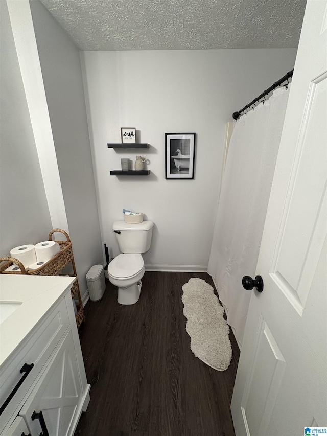 full bath with a textured ceiling, wood finished floors, toilet, and vanity