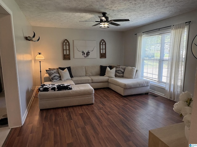 living area featuring dark wood finished floors, baseboards, and a textured ceiling