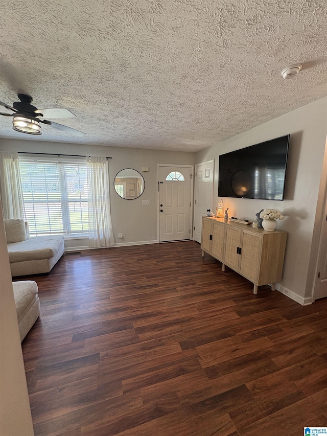 unfurnished living room with dark wood-style floors, a textured ceiling, ceiling fan, and baseboards