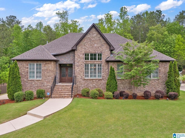 view of front of house with a front lawn, french doors, and brick siding