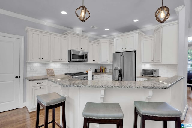 kitchen with tasteful backsplash, white cabinets, appliances with stainless steel finishes, and light wood-style floors