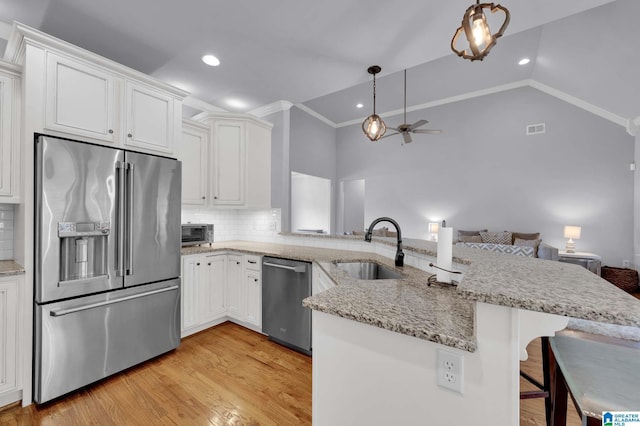 kitchen featuring stainless steel appliances, backsplash, a peninsula, and a sink