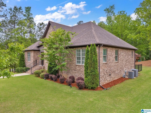 view of property exterior with brick siding, a shingled roof, and a yard