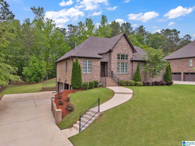 english style home featuring a front yard, a garage, a shingled roof, driveway, and brick siding