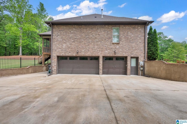 view of home's exterior with driveway, an attached garage, fence, stairway, and brick siding