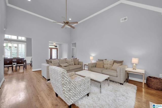 living room with wood finished floors, ceiling fan with notable chandelier, baseboards, visible vents, and high vaulted ceiling