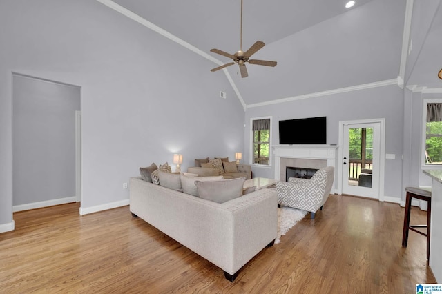 living room featuring a healthy amount of sunlight, high vaulted ceiling, a tile fireplace, and baseboards