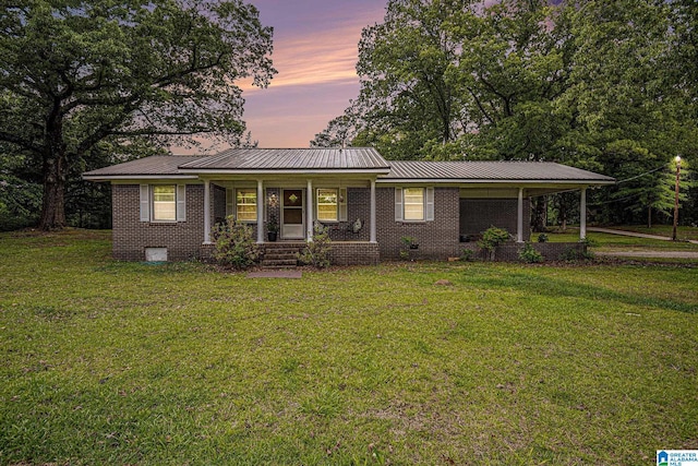 single story home featuring a porch, a front lawn, metal roof, and brick siding