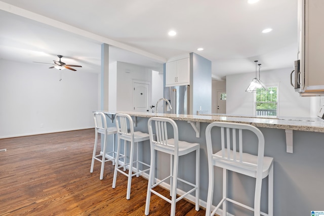 2607 Woodfern Ct, Homewood, AL 35209 - kitchen with a breakfast bar, light stone counters, a ceiling fan, dark wood finished floors, and appliances with stainless steel finishes