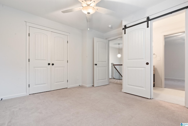 2607 Woodfern Ct, Homewood, AL 35209 - unfurnished bedroom featuring a closet, light carpet, baseboards, ceiling fan, and a barn door