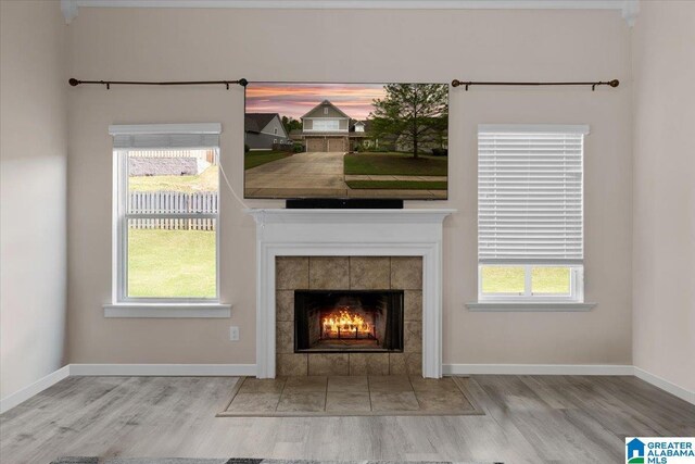 interior details featuring baseboards, a tiled fireplace, and wood finished floors