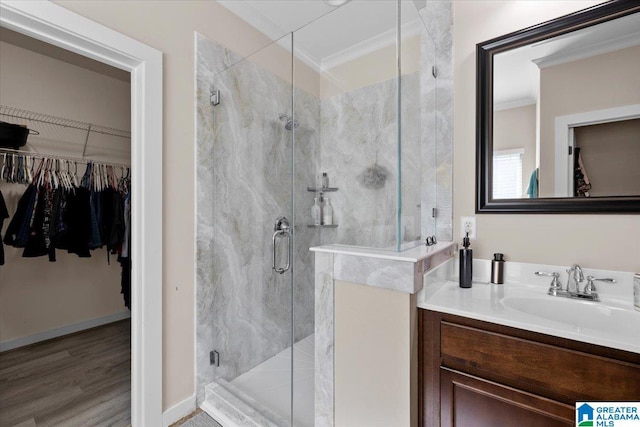 bathroom featuring crown molding, wood finished floors, vanity, a spacious closet, and a marble finish shower