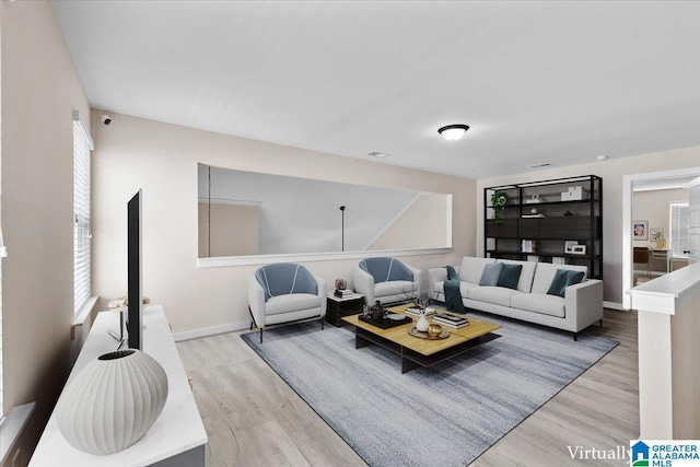 living area with a healthy amount of sunlight, baseboards, and light wood finished floors