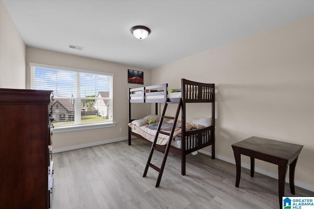 bedroom with visible vents, light wood-style flooring, and baseboards