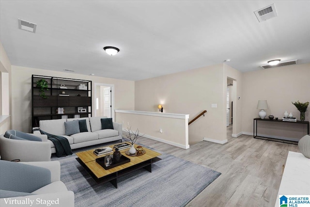living room with baseboards, visible vents, and wood finished floors
