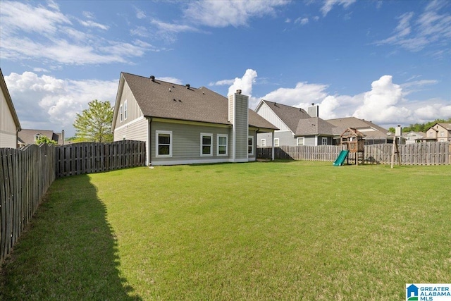 rear view of property with a fenced backyard, a playground, a yard, and a chimney