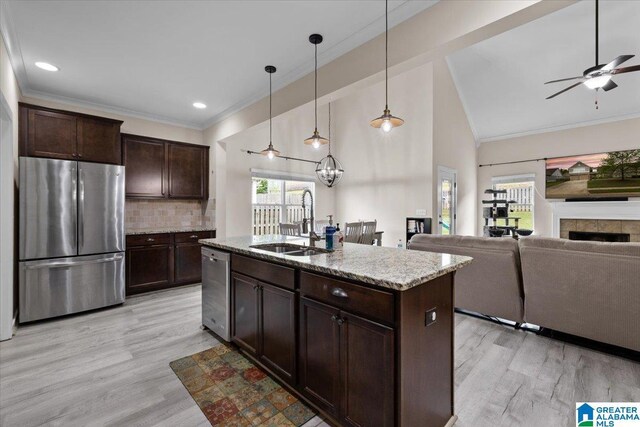 kitchen with a sink, appliances with stainless steel finishes, crown molding, and light wood-style flooring