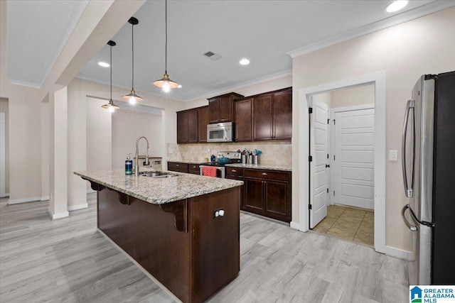 kitchen featuring a sink, ornamental molding, a breakfast bar, stainless steel appliances, and light wood-style flooring