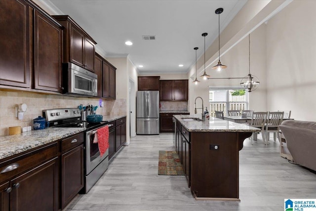 kitchen featuring visible vents, light stone countertops, light wood-type flooring, a sink, and stainless steel appliances