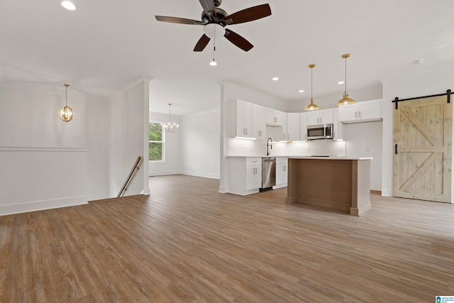 670 Hillstone Dr, Pell City, AL 35125 - kitchen with a barn door, stainless steel appliances, light countertops, open floor plan, and light wood finished floors