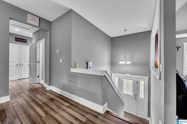 foyer entrance featuring a high ceiling, a notable chandelier, wood finished floors, and baseboards