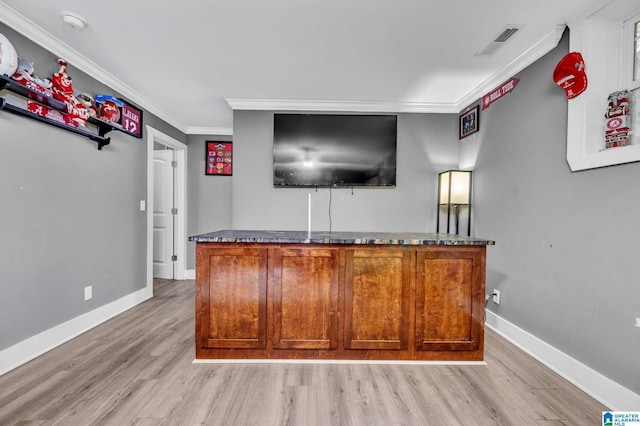 bar with visible vents, light wood-type flooring, ornamental molding, and baseboards