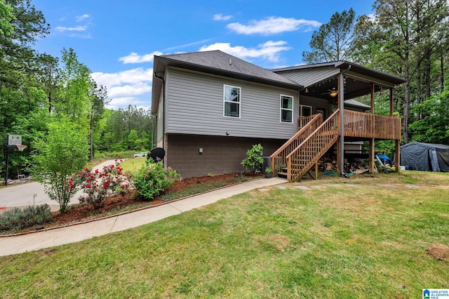 back of house featuring a ceiling fan, stairs, and a lawn