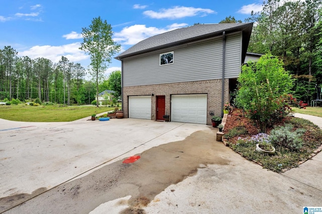 view of side of property featuring a garage, brick siding, driveway, and a yard