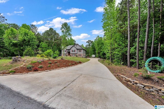 view of front of house with driveway and a wooded view