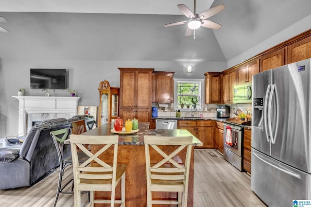 kitchen with a sink, light wood-style floors, ceiling fan, appliances with stainless steel finishes, and open floor plan