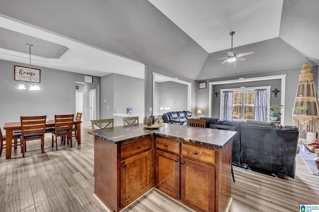 kitchen with open floor plan, a raised ceiling, light wood-type flooring, and a ceiling fan