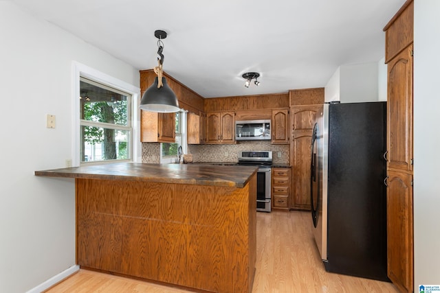 3516 Griffitt Bend Rd, Talladega, AL 35160 - kitchen with stainless steel appliances, dark countertops, a peninsula, light wood-style flooring, and brown cabinets