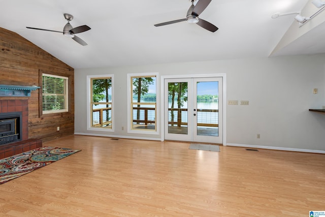 3516 Griffitt Bend Rd, Talladega, AL 35160 - unfurnished living room featuring vaulted ceiling, a ceiling fan, wood walls, wood finished floors, and a tile fireplace