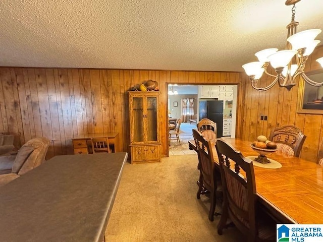dining room with an inviting chandelier, a textured ceiling, and wood walls