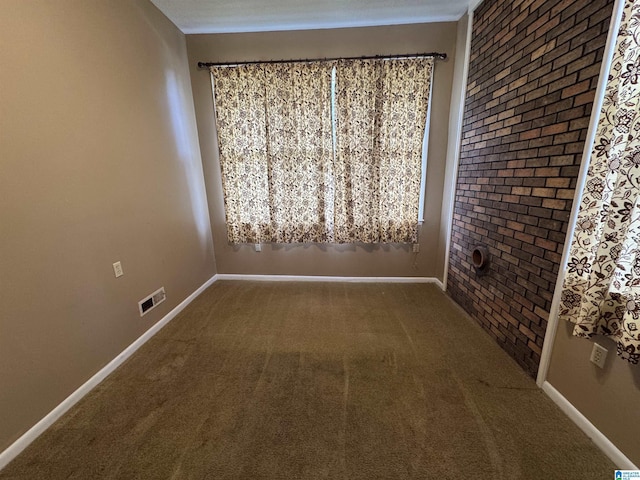 spare room featuring visible vents, brick wall, baseboards, and carpet floors