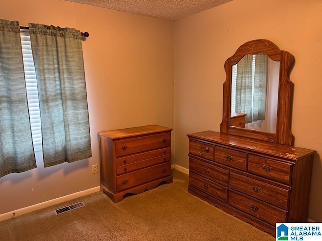 bedroom with a textured ceiling, visible vents, carpet floors, and baseboards