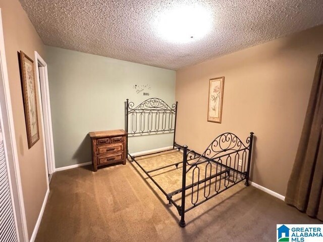 carpeted bedroom with a textured ceiling and baseboards