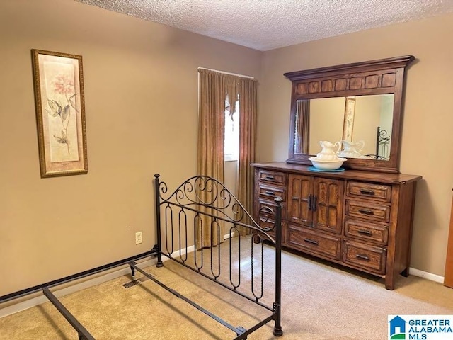 bedroom with baseboards, a textured ceiling, and light colored carpet