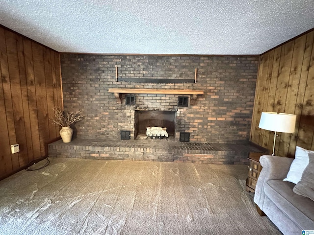 unfurnished living room with wood walls, a textured ceiling, carpet floors, and a brick fireplace