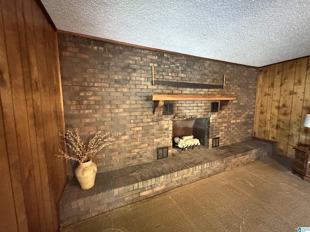 unfurnished living room with wooden walls, a textured ceiling, carpet floors, and a fireplace