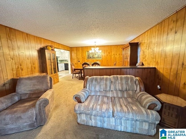 bedroom with a chandelier, wooden walls, a textured ceiling, and carpet flooring