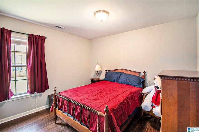bedroom featuring baseboards, visible vents, and wood finished floors