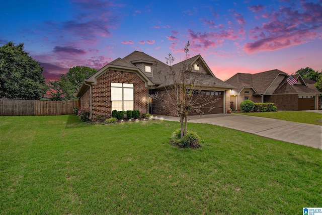 view of front of house with fence, an attached garage, brick siding, a yard, and driveway