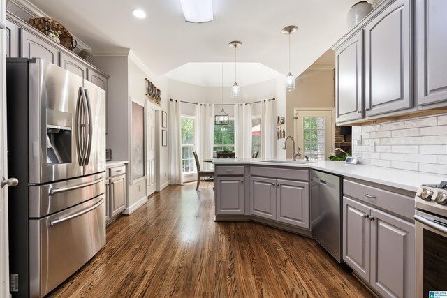 kitchen with appliances with stainless steel finishes, gray cabinets, a sink, a peninsula, and crown molding