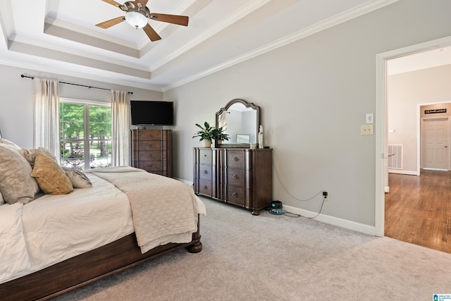 carpeted bedroom featuring ornamental molding, a raised ceiling, baseboards, and ceiling fan