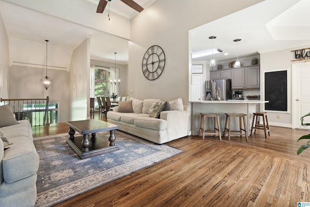living area featuring wood finished floors, crown molding, ceiling fan, and a chandelier