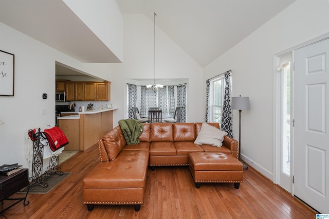 20443 Hepzibah Church Rd, Mccalla, AL 35111 - living area featuring high vaulted ceiling, baseboards, light wood finished floors, and a notable chandelier