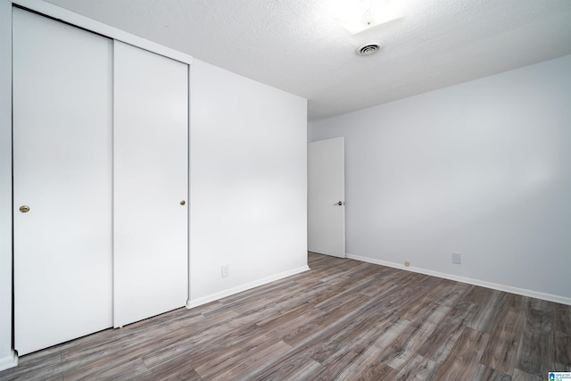 unfurnished bedroom featuring baseboards, visible vents, wood finished floors, and a closet