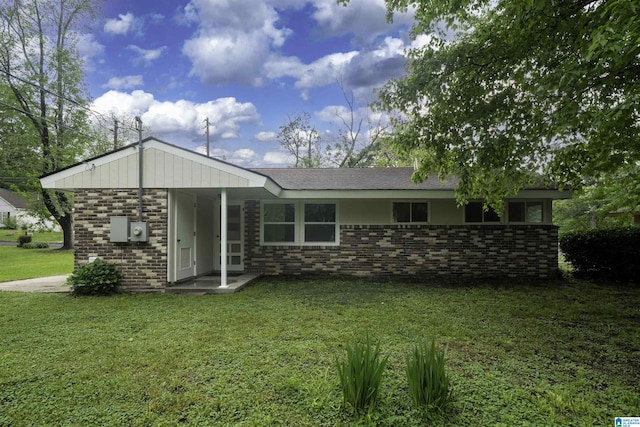back of property with brick siding and a yard