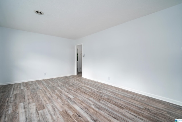 unfurnished room featuring wood finished floors, visible vents, and baseboards